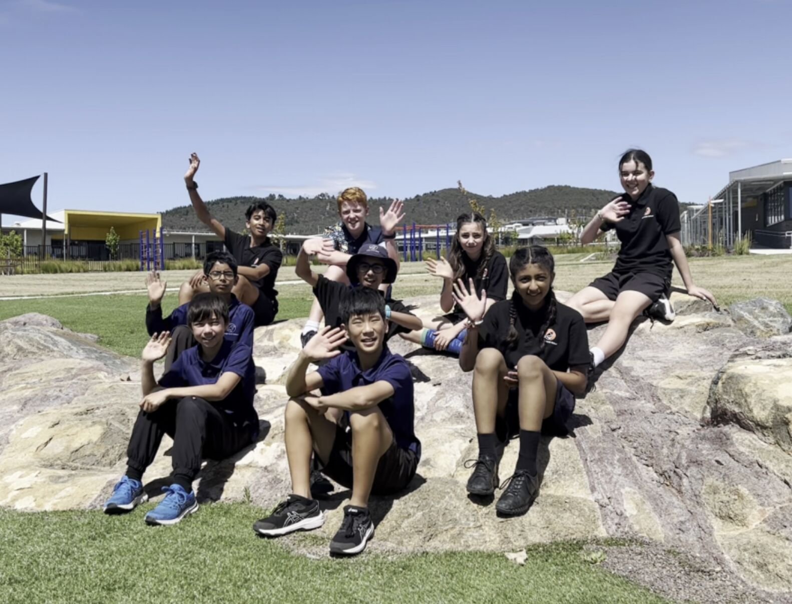Evelyn Scott School students waving from the rocks on their school grounds